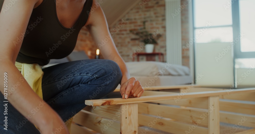 A woman assembles a wooden shelf using a screwdriver in a stylish home interior A woman assembles a wooden shelf using a screwdriver in a stylish home interior