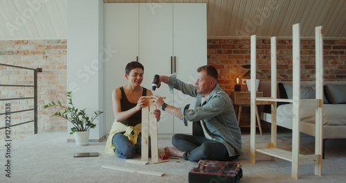 Fotografie A man and a woman assemble a shelving at home, they use a screwdriver, talk and
