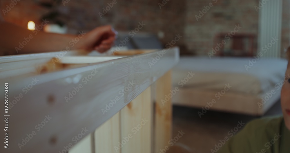 Mom and son paint a wooden rack with a brush in a stylish home interior, working together, close-up of hands, no faces Mom and son paint a wooden rack with a brush in a stylish home interior, working together, close-up of hands, no faces