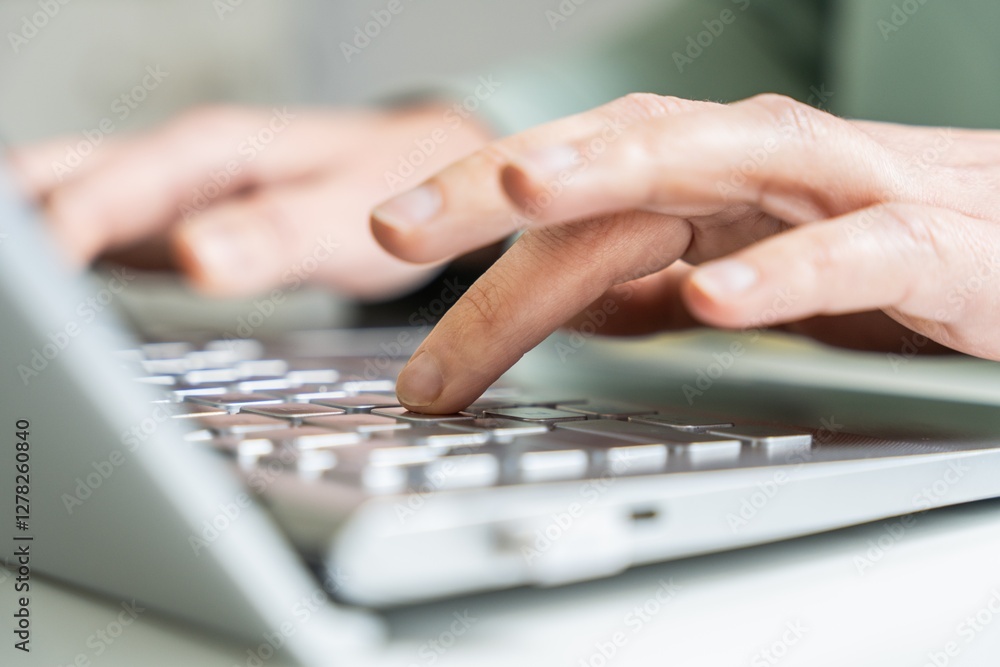 Hands typing on a laptop keyboard, close-up of finger pressing key Hands typing on a laptop keyboard, close-up of finger pressing key