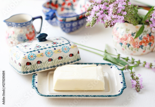 Beautiful ceramic butter dish  with butter briquettes on the kitchen table. Selective focus.