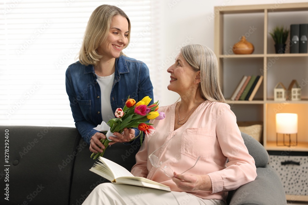 Smiling daughter congratulating her mom with bouquet of tulips at home. Happy Mother's Day Smiling daughter congratulating her mom with bouquet of tulips at home. Happy Mother's Day