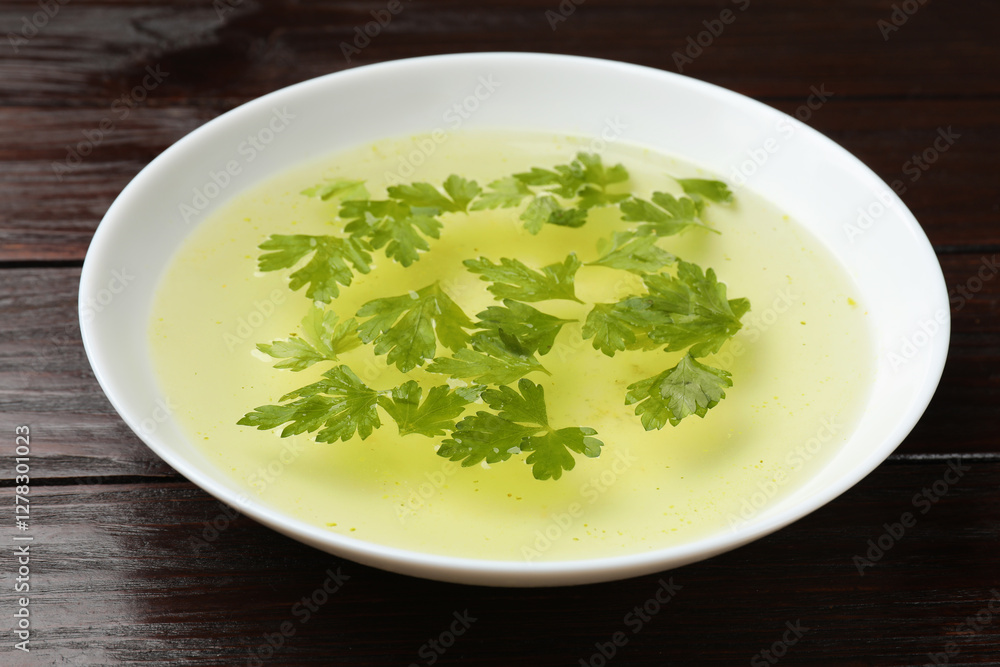 Tasty chicken bouillon in bowl on wooden table, closeup Tasty chicken bouillon in bowl on wooden table, closeup