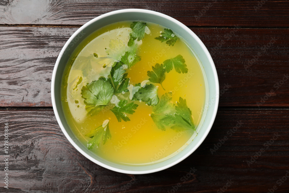 Tasty chicken bouillon in bowl on wooden table, top view Tasty chicken bouillon in bowl on wooden table, top view