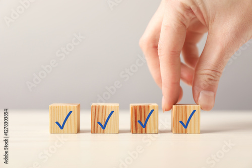 Woman taking cube with check mark at table, closeup