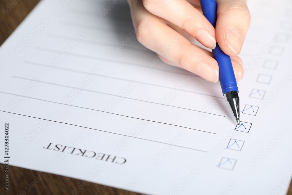 Woman filling Checklist with pen at table, closeup Woman filling Checklist with pen at table, closeup