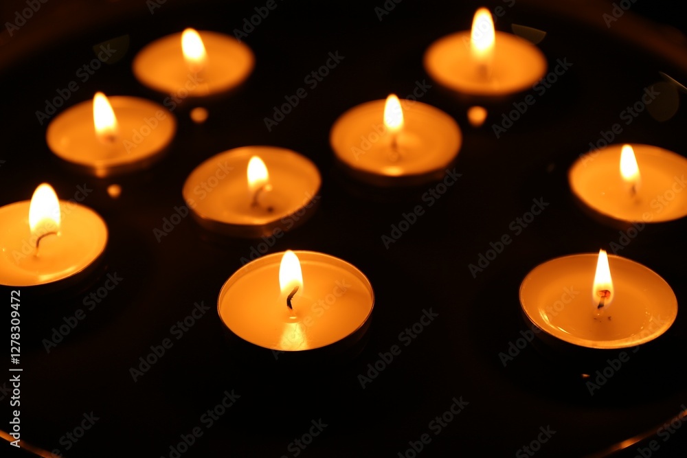 Many burning candles on dark surface, closeup Many burning candles on dark surface, closeup