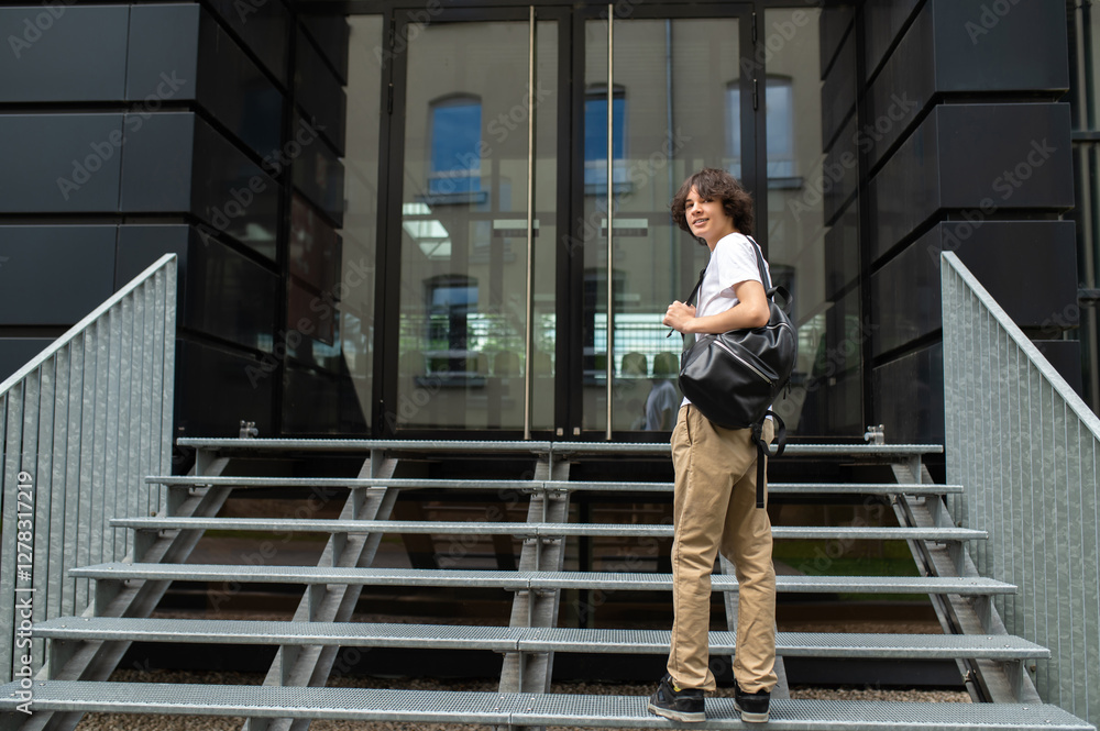 Young tall caucasian guy in white tshirt on the steps at the building entrance Young tall caucasian guy in white tshirt on the steps at the building entrance