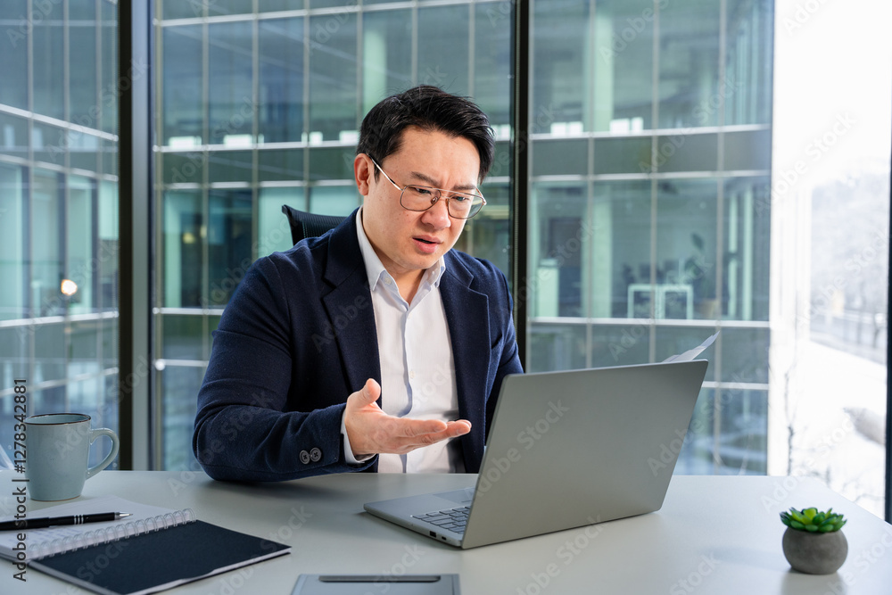 Professional Asian businessman focused on tasks, working in bright, sophisticated modern office. Professional Asian businessman focused on tasks, working in bright, sophisticated modern office.