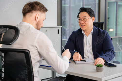 Businesspeople engaged in a productive conversation, collaborating in a bright and modern office room. Participants appear engaged and confident, showcasing professionalism in workplace context.