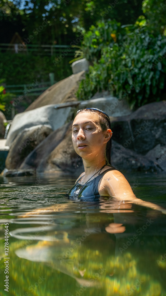 Fototapeta premium Mujer relajada flontando en medio del agua de la piscina natural