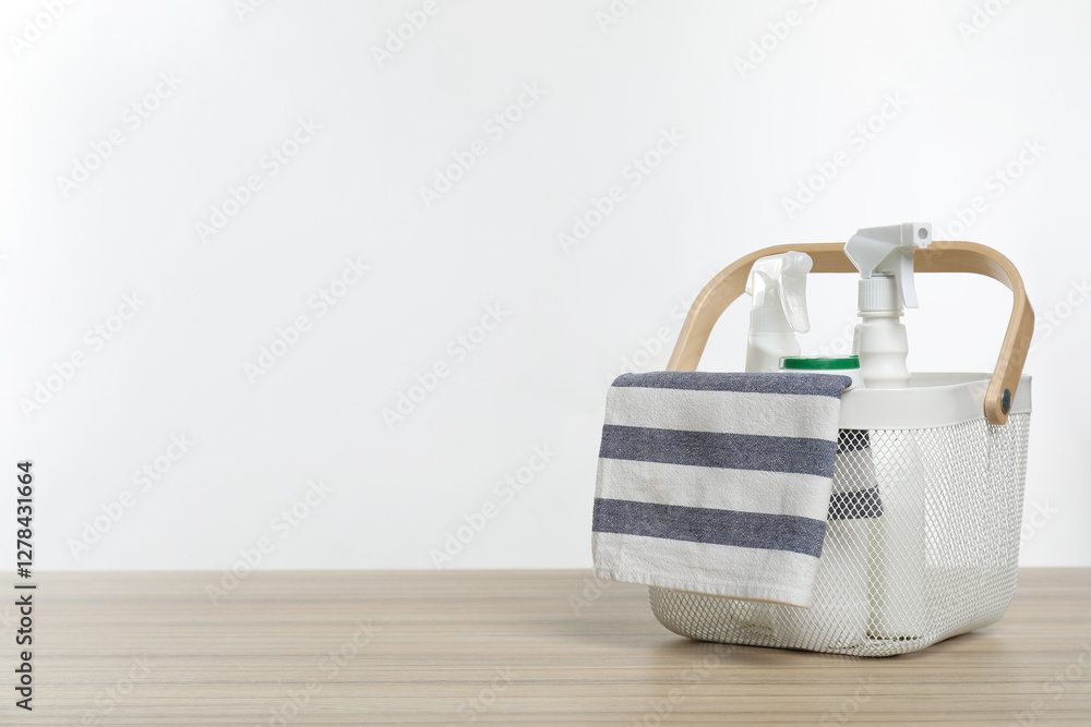 Obraz premium Different cleaning products and rag in basket on wooden table, space for text