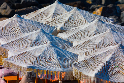 Obraz na płótnie Woven white parasols arranged closely together, providing shade at beach. Detailed pattern of parasols fabric, along with fringe hanging from edges, creates an aesthetically pleasing w salonie