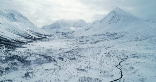 Drone slow-motion flight over snowy valley surrounded by towering peaks in blue hour, epic winter landscape, cinematic high mountains in Norway 4K aerial view DCI