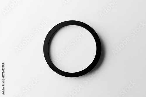 A black circular frame rests on a white surface, emphasizing a minimalist design. The clean lines and contrast create a striking visual effect, perfect for artistic display