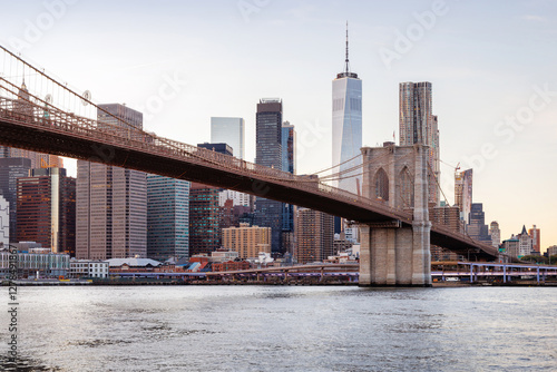 A panoramic sunset view of the Brooklyn Bridge stretching towards Manhattan