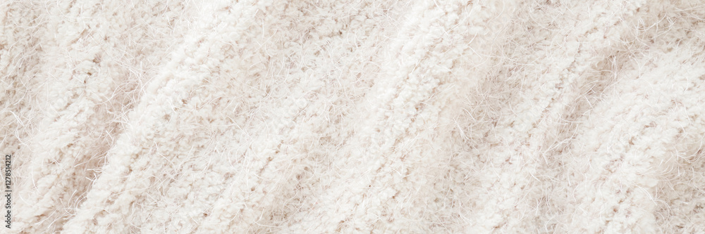 Light white hairy wavy soft knitted fabric background. Closeup. Wide banner. Top down view. Light white hairy wavy soft knitted fabric background. Closeup. Wide banner. Top down view.