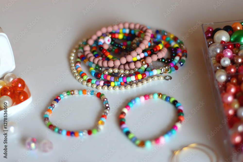 Friendship bracelet spelled with letter beads. Colorful handmade bracelets and various jewelry making supplies. Selective focus, white background.
