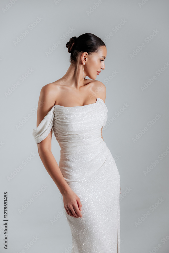 Elegance Portrait of a brunette girl in a white beige dress with sequins under the light in the studio Elegance Portrait of a brunette girl in a white beige dress with sequins under the light in the studio