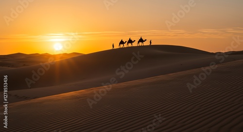 Fototapeta Naklejka Na Ścianę i Meble -  Camel Caravan Riding Across Desert Sand Dunes at Dramatic Sunset