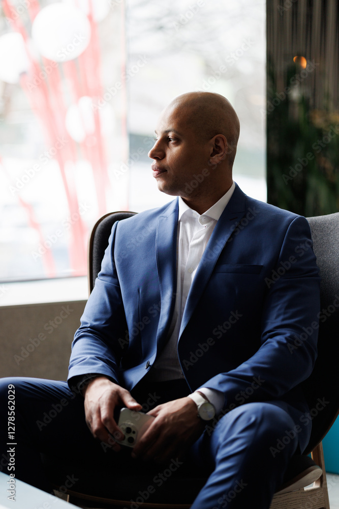 African american businessman holding smartphone in hotel lobby African american businessman holding smartphone in hotel lobby
