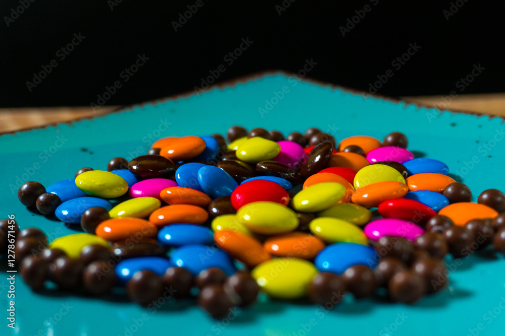 Close-up of colorful chocolate candies on a vibrant turquoise plate, perfect for food and confectionery themes Close-up of colorful chocolate candies on a vibrant turquoise plate, perfect for food and confectionery themes