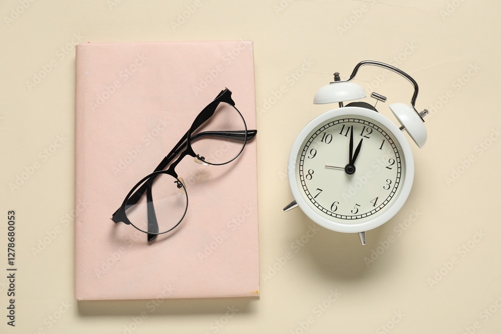 Alarm clock, glasses and book on beige background, flat lay. Time for knowledge Alarm clock, glasses and book on beige background, flat lay. Time for knowledge