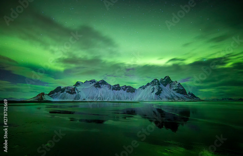 Vestrahorn reflected in the water in northen lights in Iceland