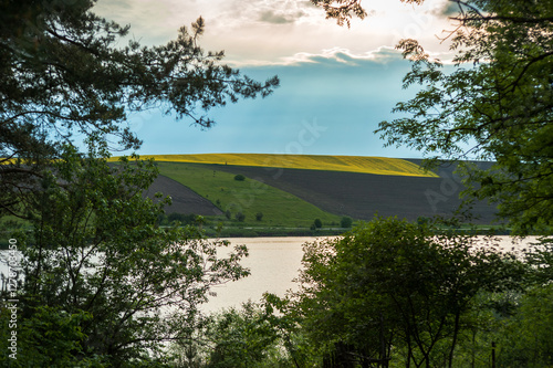 view of reservoir, hills with fields of sunflowers and lush greenery through ...