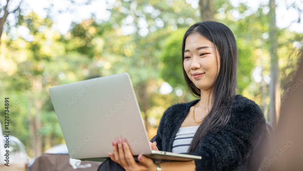 beautiful asian woman working on laptop while sitting in the park beautiful asian woman working on laptop while sitting in the park