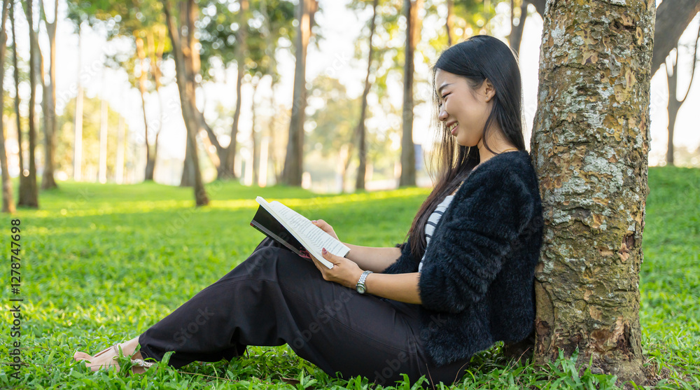 Happy girl reading a book sitting under the tree in park outdoor Happy girl reading a book sitting under the tree in park outdoor