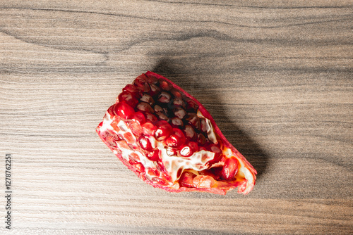 O peace of a Pomegrenade with the seeds inside, on a wooden background. photo