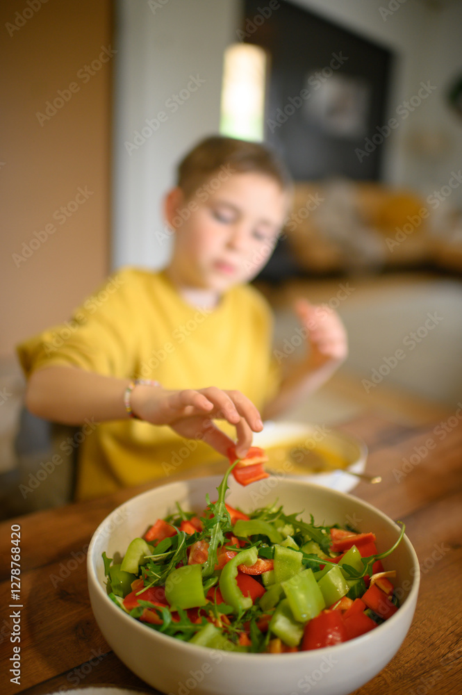 A young boy enjoys a healthy meal with his family, eating soup and salad with great appetite. The scene reflects wholesome nutrition, warmth, and togetherness at the dining table. A young boy enjoys a healthy meal with his family, eating soup and salad with great appetite. The scene reflects wholesome nutrition, warmth, and togetherness at the dining table.