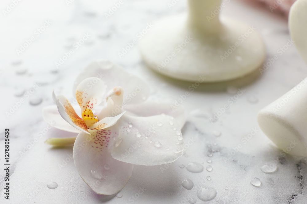 Orchid flower and spa stones on white marble table, closeup Orchid flower and spa stones on white marble table, closeup