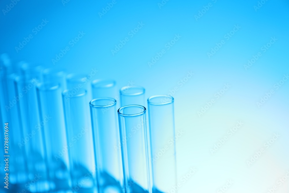 Test tubes on light blue background, space for text. Laboratory glassware Test tubes on light blue background, space for text. Laboratory glassware