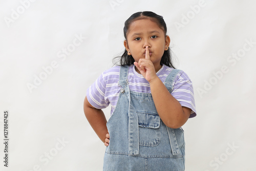 Fotografie Adorable asian little girl standing while making quite hand gesture