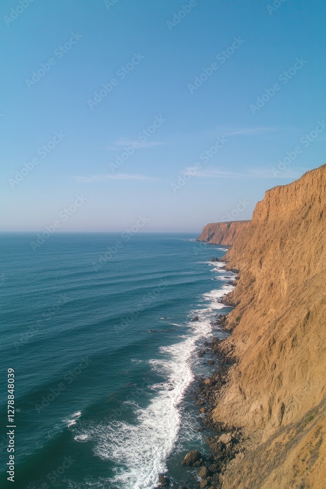 Coastal cliffs rise dramatically above tranquil waves under clea