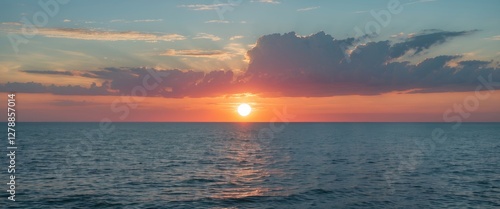 Sunset over calm ocean water with clouds on the horizon and vibrant sky colors during twilight hours photo