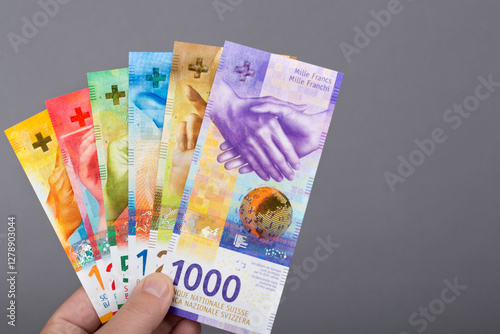 Swiss franc in the hand on a gray background