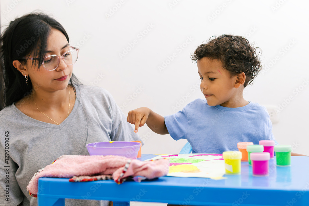 Fototapeta premium Latin mother supports her child’s development while painting together, encouraging creativity and learning