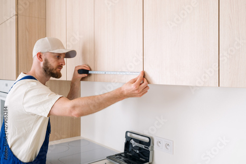 Professional handyman measuring cabinet height during apartment renovation process