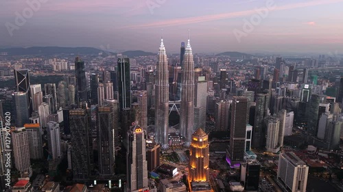 Kuala Lumpur skyline near KLCC drone video. Aerial view of Petronas Towers with pink glow from sky at dusk.