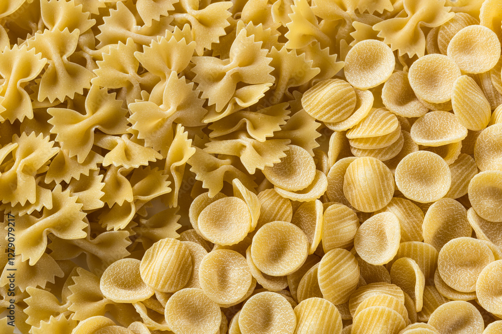 Pasta background , top view . Close-up of raw Italian durum wheat orecchiette and farfalle pasta . Pasta background , top view . Close-up of raw Italian durum wheat orecchiette and farfalle pasta .