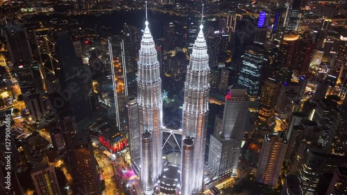 High angle aerial drone video of Petronas Towers in city center of Kuala Lumpur, Malaysia brightly illuminated in the night