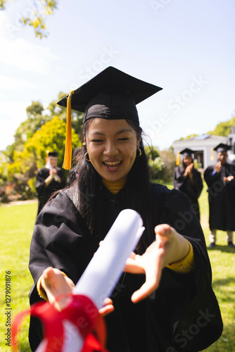 Wallpaper Mural Graduate in cap and gown joyfully reaching for diploma in garden with diverse friends Torontodigital.ca