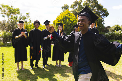 Wallpaper Mural Teen celebrating graduation in garden with diverse friends clapping and smiling in background Torontodigital.ca