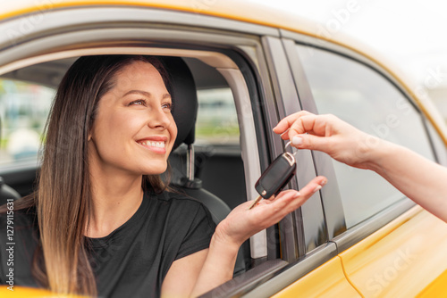 Obraz na płótnie A smiling woman sitting in a yellow car receives a set of keys from another person, symbolizing a car purchase, rental, or ownership transfer. w salonie