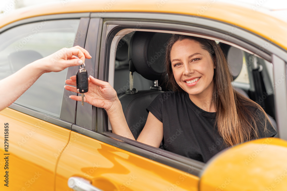 A smiling woman sitting in a yellow car receives a set of keys from another person, symbolizing a car purchase, rental, or ownership transfer.