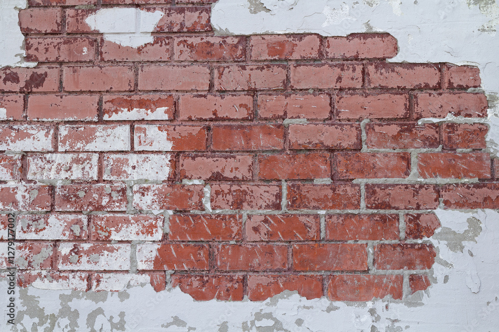 Weathered brick surface with cracked plaster and exposed red bricks