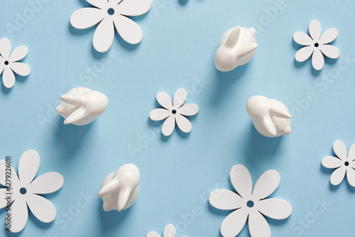 Minimalist Easter pattern with white bunnies and flowers on blue background.